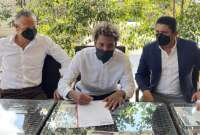 Esteban Paz (izq.) observa a Joao Ortiz firmar el contrato. A la derecha, José Delgado, presidente del Delfín.