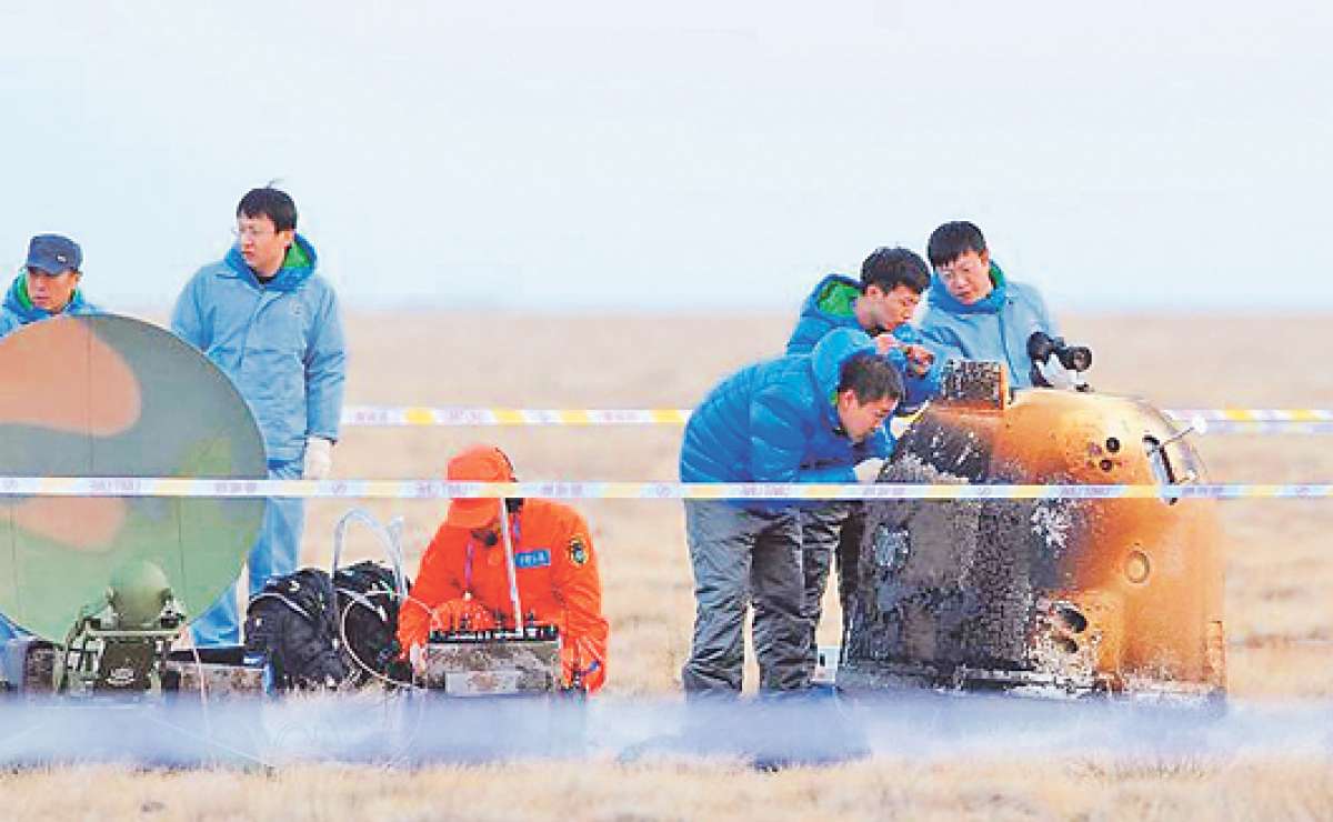 T&eacute;cnicos chinos revisan la sonda espacial que aterriz&oacute; en la Tierra el pasado s&aacute;bado. La nave tuvo que soportar altas temperaturas al ingresar a la &oacute;rbita terrestre. Foto: Agencia de noticias Xinhua