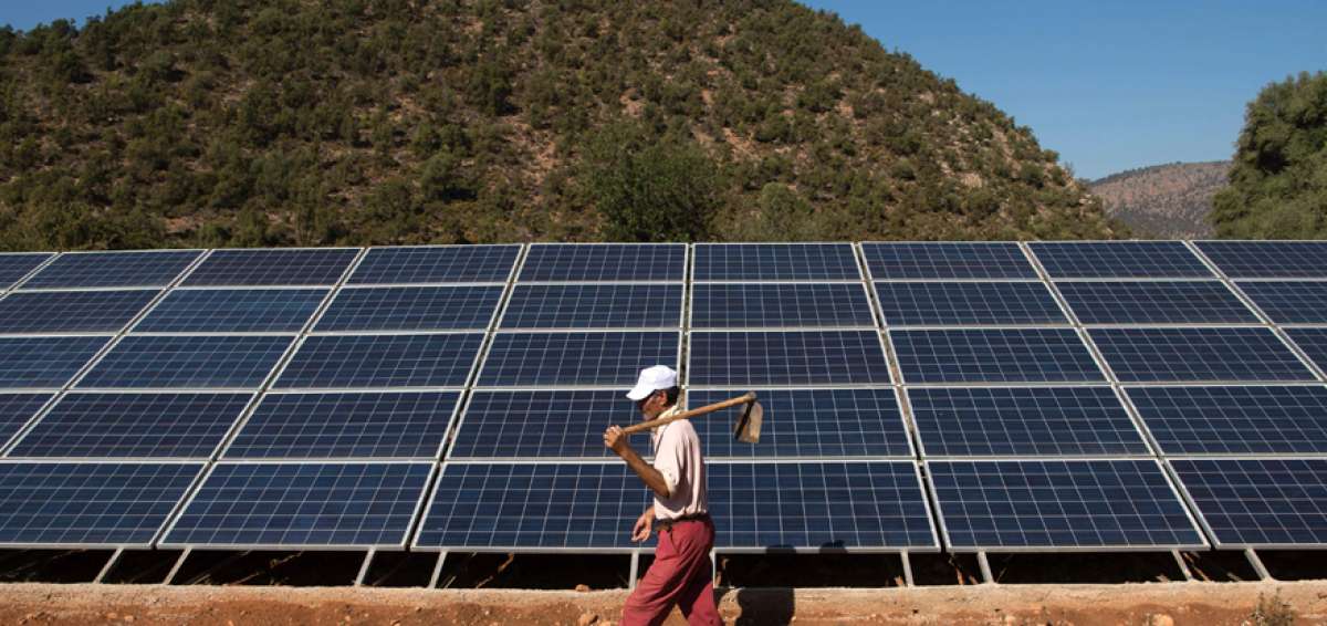 Un agricultor marrueco camina junto a paneles solares que est&aacute;n conectados a un generador. Este sistema ayuda a extraer agua debajo de la tierra.