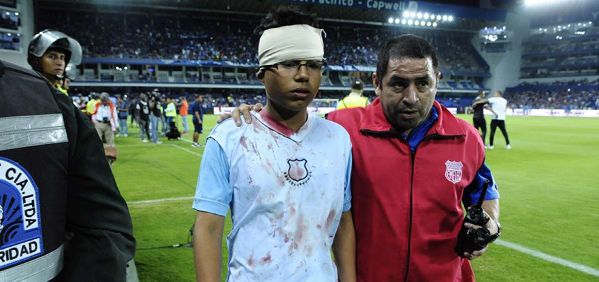 Un hincha de Emelec, con su camiseta ensangrentada, es atendido tras sufrir golpes en el estadio Capwell.  