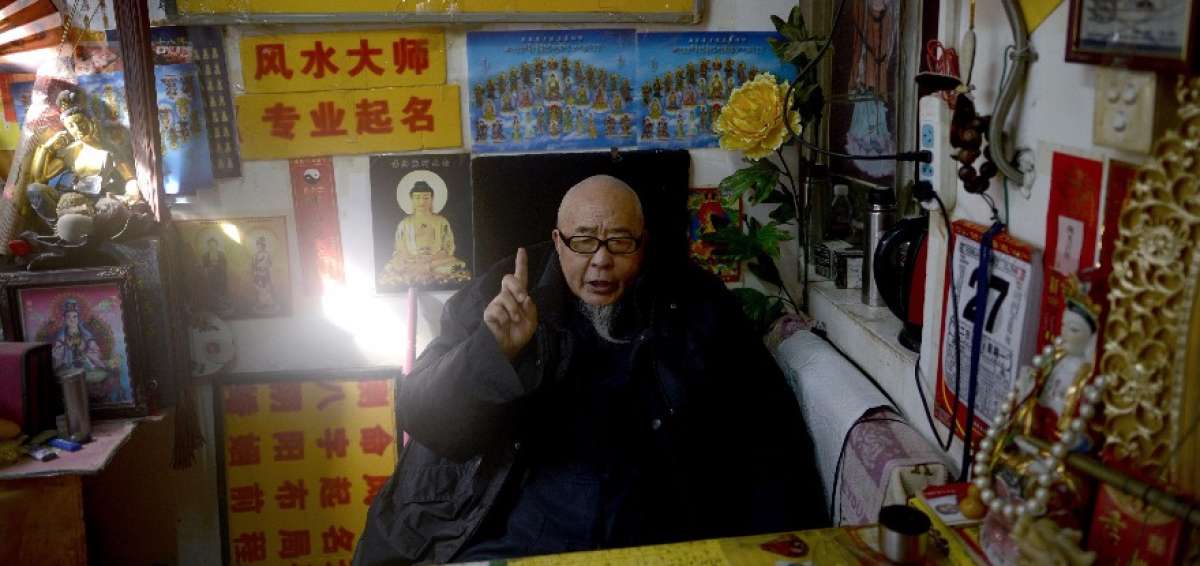 Mao Shandong espera a los clientes en su tienda de poner nombres en China. Los negocios en l&iacute;nea le disminuyeron los contratos.  