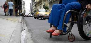 En la calle Pichincha, una mujer en silla de ruedas, se acerca a una rampa para subir la vereda.