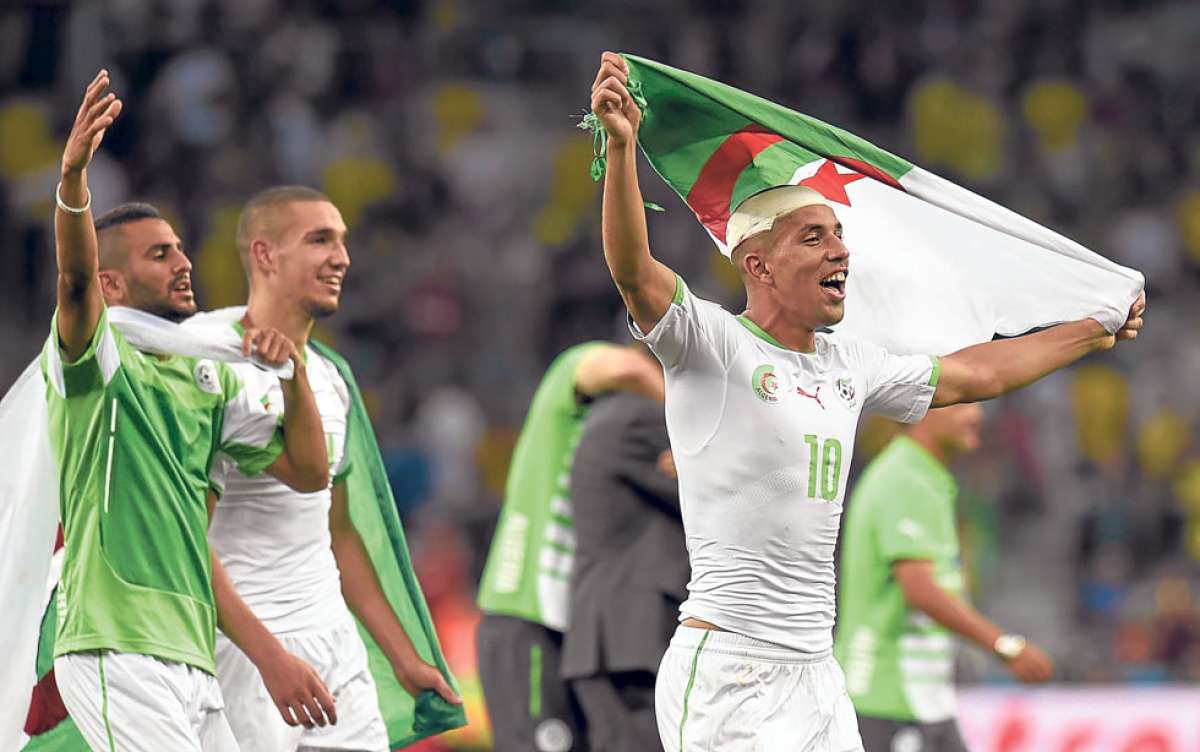El jugador de Argelia, Sofiane Feghouli (derecha), celebra la clasificaci&oacute;n a octavos de final con su bandera. Foto: AFP