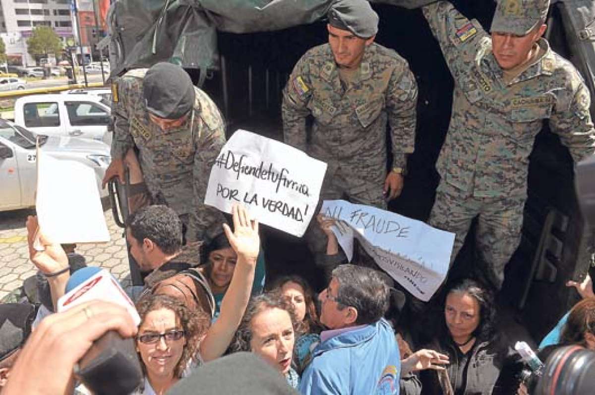 Integrantes del colectivo Yasunidos en momentos en que imped&iacute;an a los militares colocar las cajas de las firmas en un cami&oacute;n. Foto: &Aacute;lvaro P&eacute;rez.