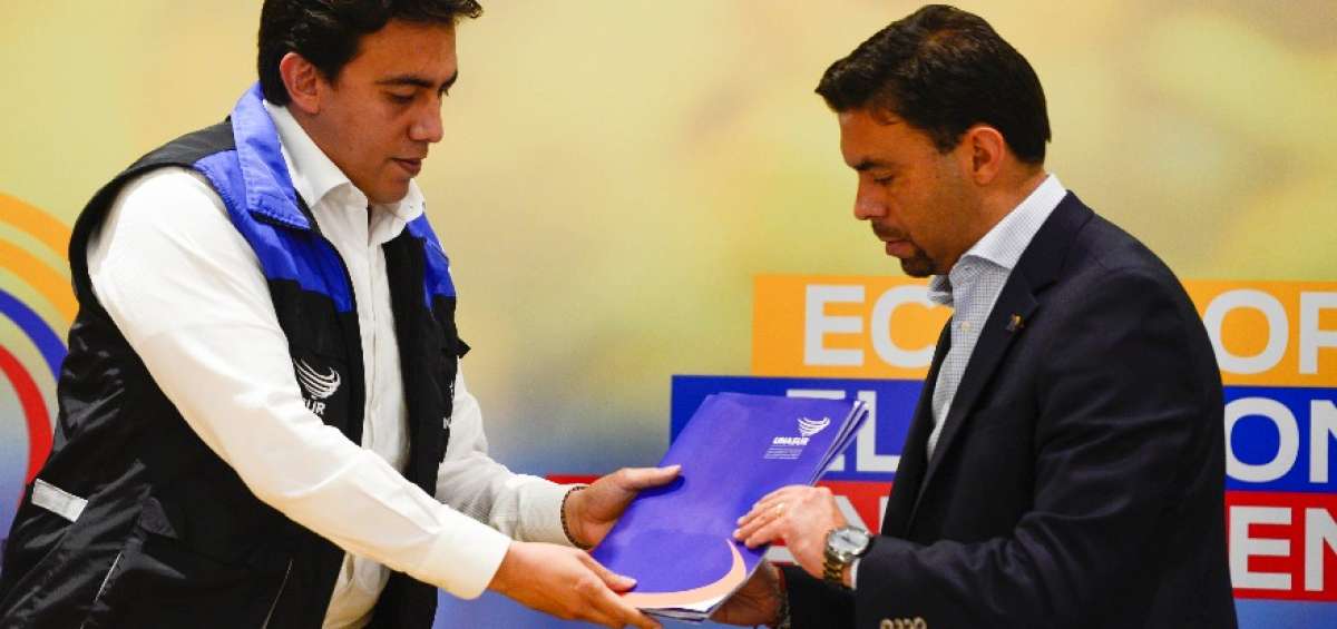 El jefe de misi&oacute;n de la Unasur, Alexander Vega (izq.), entrega el informe al titular del CNE, Juan Pablo Pozo.