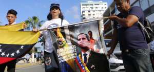 Venezolanos residentes en Ecuador sostienen un afiche con la imagen del mandatario interino de su pa&iacute;s en espera de su llegada al balneario de Salinas, la tarde del s&aacute;bado.  
