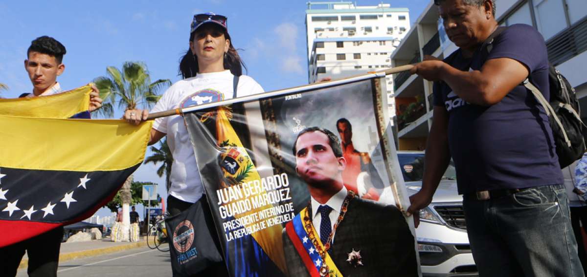 Venezolanos residentes en Ecuador sostienen un afiche con la imagen del mandatario interino de su pa&iacute;s en espera de su llegada al balneario de Salinas, la tarde del s&aacute;bado.  
