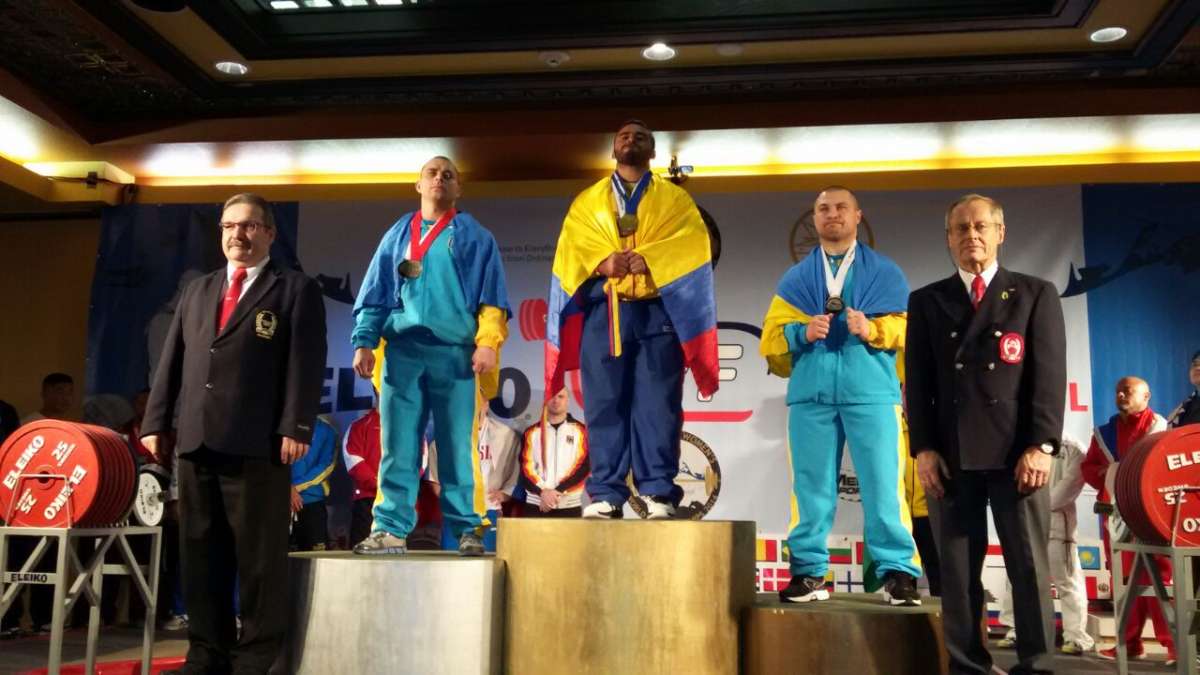 El levantador de potencia ecuatoriano Jos&eacute; Castillo (c.) festeja su medalla de oro con la bandera tricolor. Foto: Cortes&iacute;a 