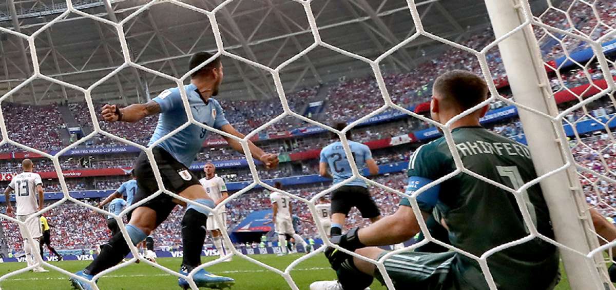 Luis Su&aacute;rez (izq.) celebra el segundo tanto de Uruguay (un autogol de Denis Cheryshev); desde el piso, el arquero ruso Igor Akinfeev yace resignado.