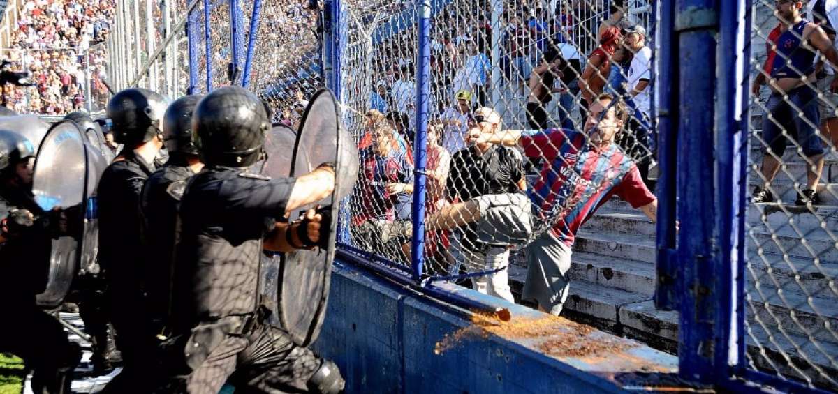 Un hincha argentino lanza bancas de pl&aacute;stico a miembros de la Polic&iacute;a, en el interior de un estadio.