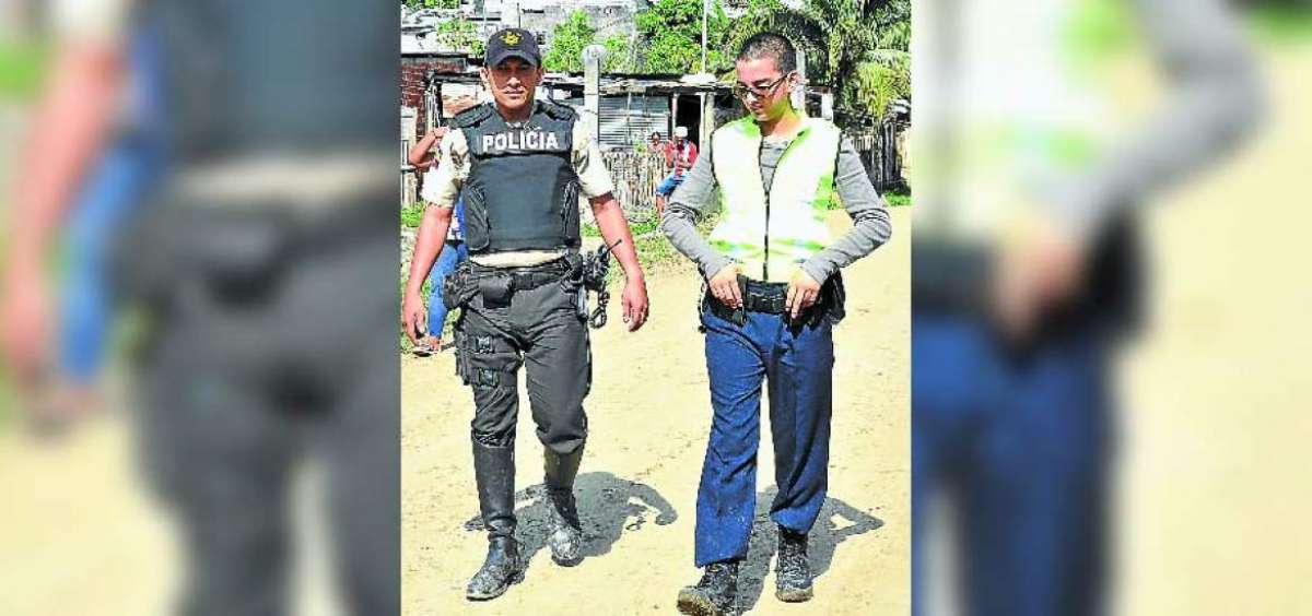 Roberto Boh&oacute;rquez, de 18 a&ntilde;os, camina por la zona &lsquo;H&rsquo;, en el noroeste de Guayaquil, junto al polic&iacute;a Eduardo Merch&aacute;n. 