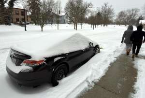 Dos personas caminan al lado de una calle afectada por la nieve este domingo en la ciudad de Hudson, Ohio (EE.UU.).