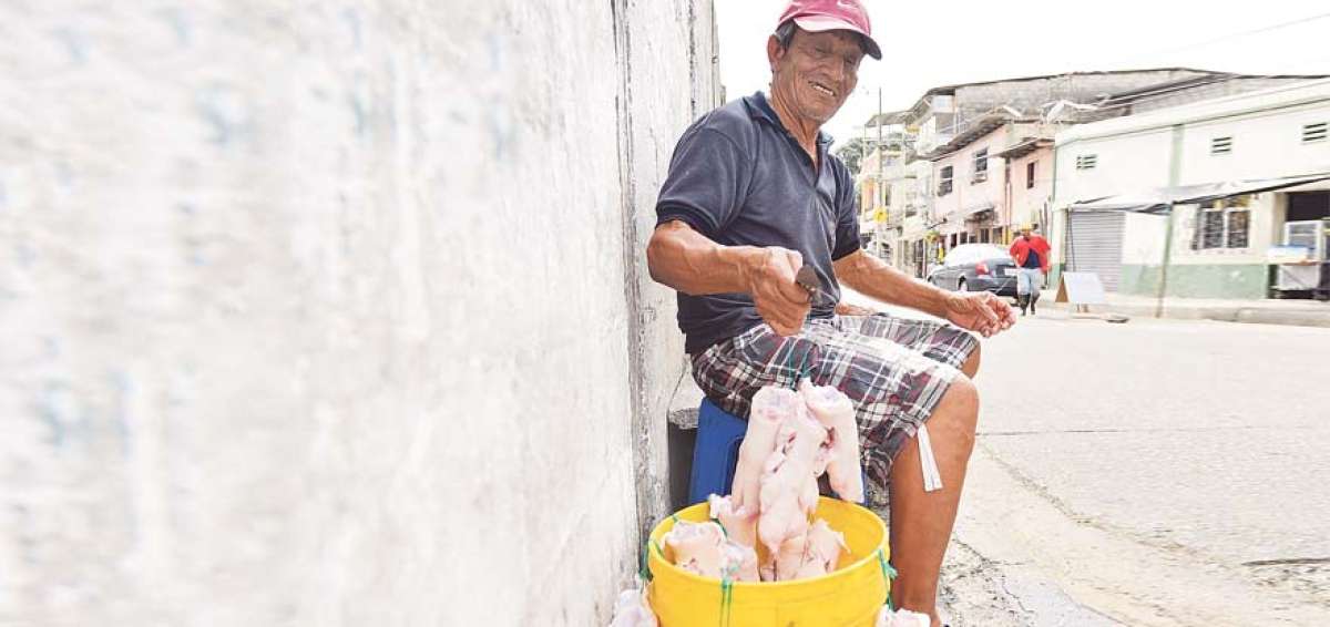 Manuel Avil&eacute;s, de 62 a&ntilde;os, limpia las extremidades porcinas en una de las calles del barrio Cuba, donde vive desde hace 40 a&ntilde;os.