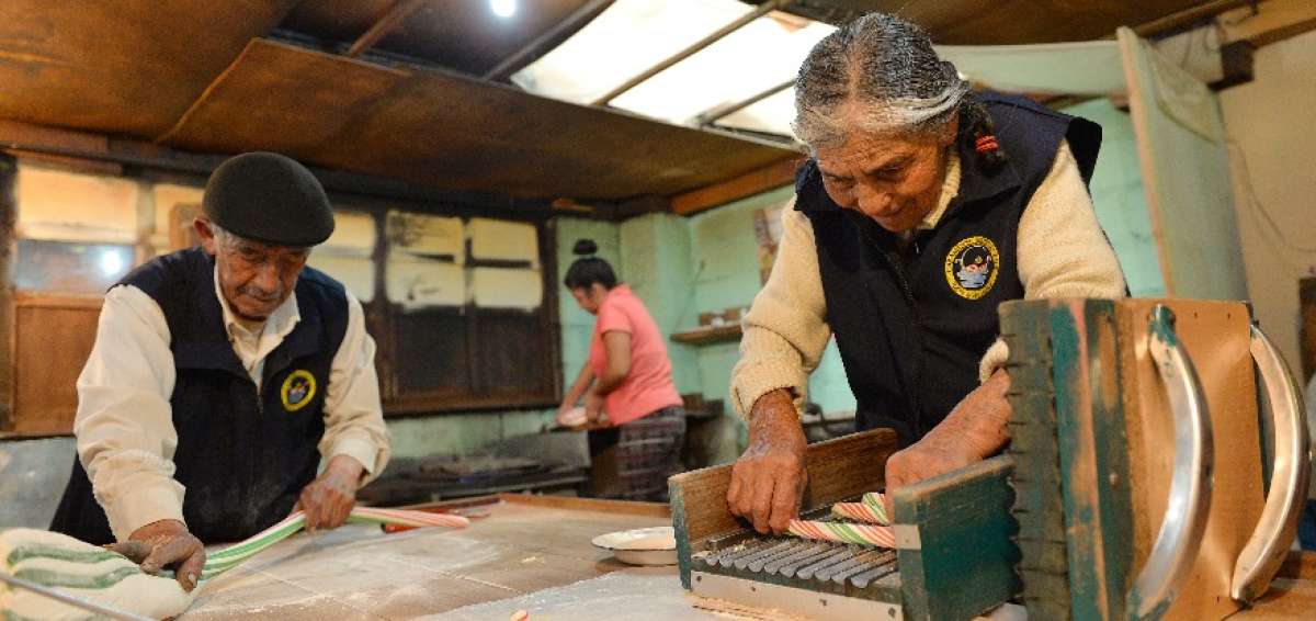 Dos piedras en plancha que se calientan a fuego lento, una mesa de madera y una vieja paila de bronce son las herramientas de don Manuel en su taller de caramelos.