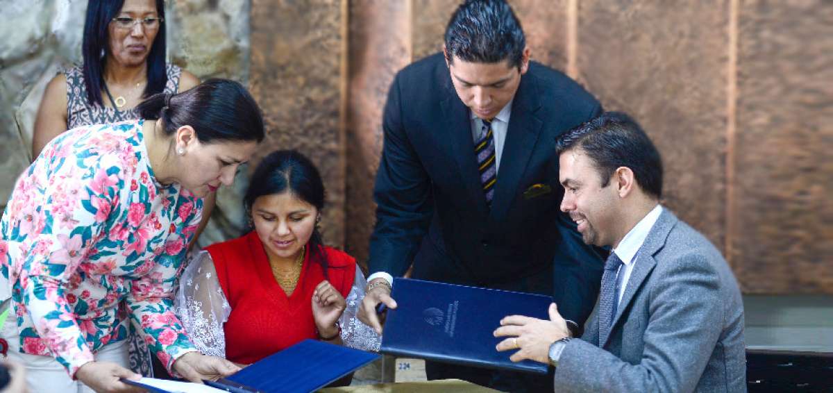 Olga Torres (sentada), de la Red Wambra Kunapac, y Juan Pablo Pozo, presidente del CNE, firman un acuerdo.