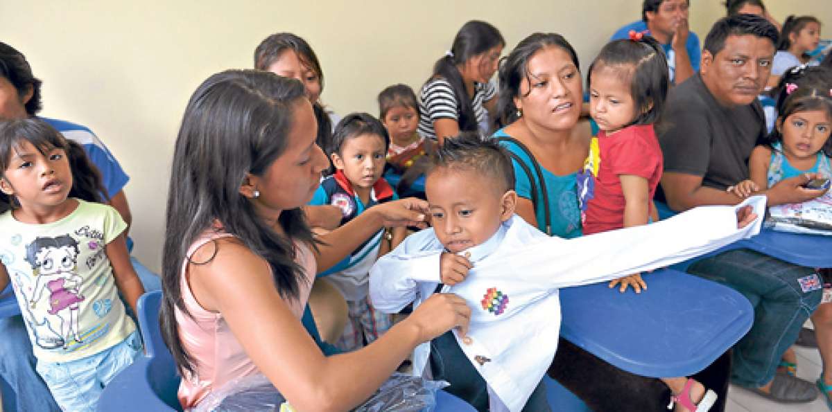 Luego de recibir el kit de 6 prendas, una de las madres beneficiadas coloca una de las camisas a su hijo. Foto: Jos&eacute; Mor&aacute;n/ El Tel&eacute;grafo