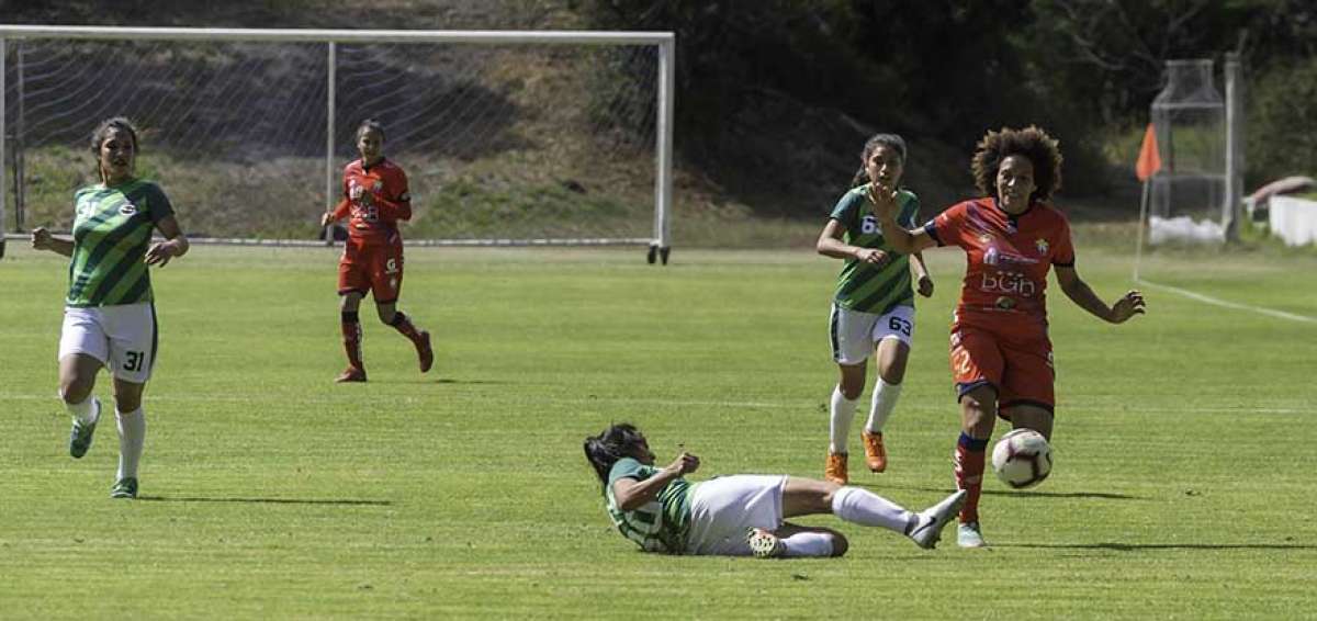 La jugadora de El Nacional, Joselyn Espinales (der.) intenta superar la marca de una futbolista de ESPE, en el partido que jugaron en Quito.