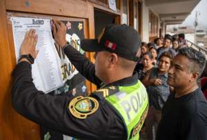 Un integrante de la Polic&iacute;a pega un cartel afuera de un aula de votaciones en el colegio Se&ntilde;or de los Milagros este lunes, en el distrito de Lur&iacute;n (Per&uacute;).