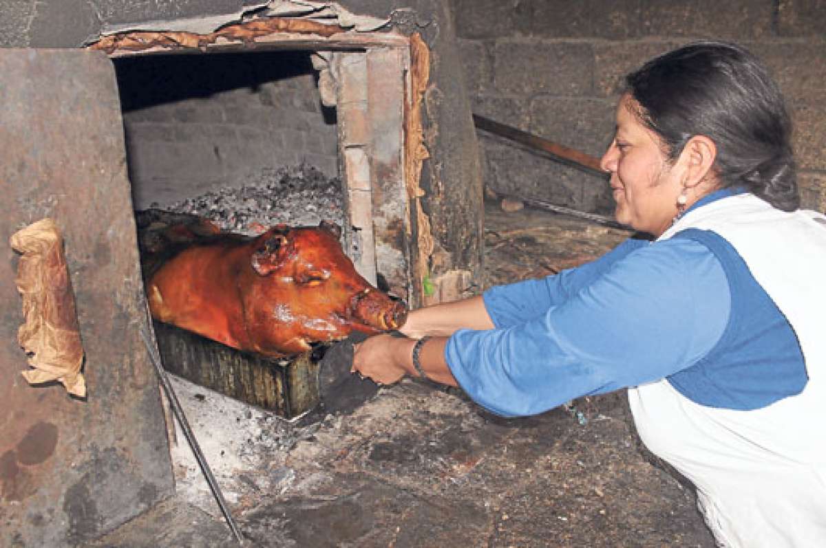 Saca cocina el cerdo en un horno de le&ntilde;a, para esto utiliza madera morocha (le&ntilde;a verde). Todos los domingos vende en el mercado 26 de Febrero de Paute. Foto: Diana Vera.