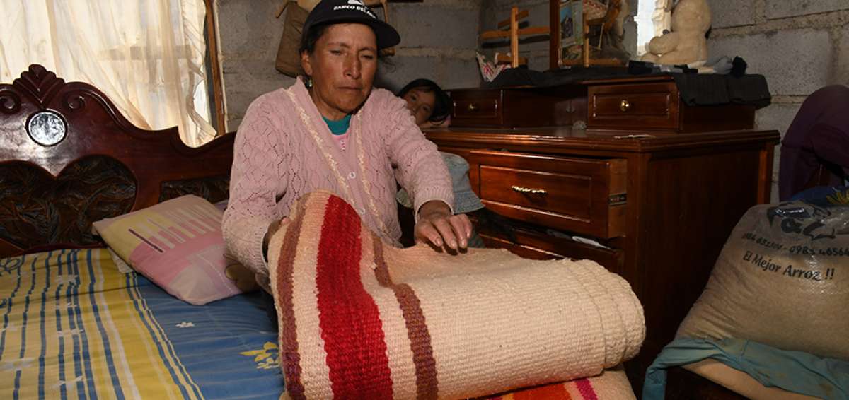 Mar&iacute;a Suqui Calle, moradora de la localidad de Cumbe, tiende en su cama una cobija de lana de borrego.  