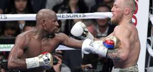 El boxeador estadounidense Floyd Mayweather (izq.) y el peleador de artes marciales mixtas Conor McGregor intercambian golpes en la T. Mobile Arena.