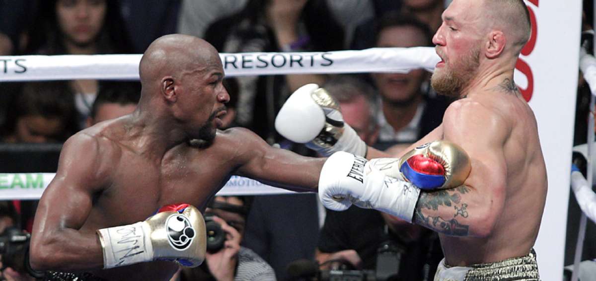 El boxeador estadounidense Floyd Mayweather (izq.) y el peleador de artes marciales mixtas Conor McGregor intercambian golpes en la T. Mobile Arena.