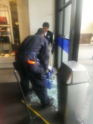 El asaltante se impact&oacute; contra la puerta de vidrio del centro comercial. El personal del centro comercial limpia los pedazos de vidrio que quedaron.  Foto: EL TEL&Eacute;GRAFO