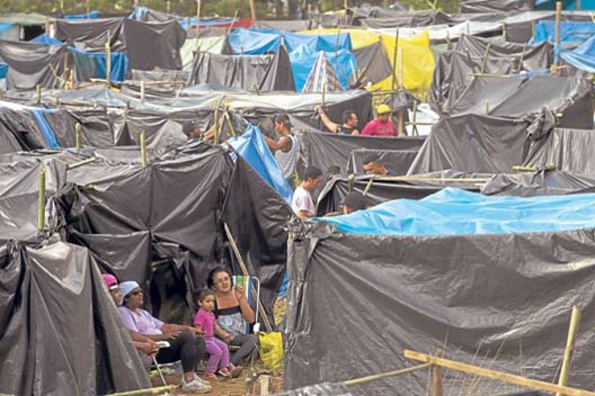 Las familias han construido viviendas improvisadas de lona y bamb&uacute; desde el fin de semana. FOTO: AFP.