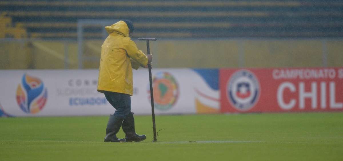 Un operario del estadio Ol&iacute;mpico Atahualpa clava una estaca en el gramado para ayudar al drenaje, en el momento de la lluvia m&aacute;s intensa, el lunes pasado.
