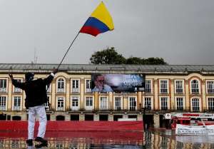 Un hombre agita una bandera frente a una valla con la fotograf&iacute;a del escritor colombiano Gabriel Garc&iacute;a M&aacute;rquez, en Bogot&aacute;. Foto: EFE