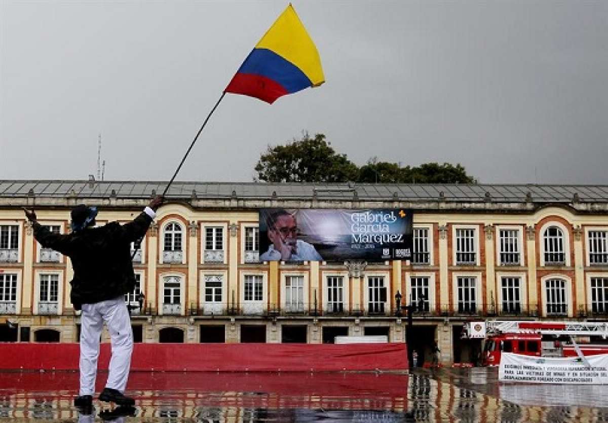 Un hombre agita una bandera frente a una valla con la fotograf&iacute;a del escritor colombiano Gabriel Garc&iacute;a M&aacute;rquez, en Bogot&aacute;. Foto: EFE