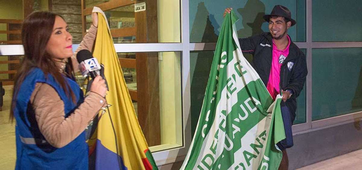 Una periodista de televisi&oacute;n y Junior Sornoza muestran la bandera de Ecuador cosida a la de Manab&iacute;.