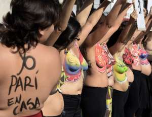 "Yo par&iacute; en casa" llevaba pintada en su espalda Eugenia Gimenez, de 29 a&ntilde;os, que pase&oacute; su torso desnudo por la c&eacute;ntrica avenida 9 de julio amamantando a su beb&eacute; de cuatro meses en brazos. FOTO: AFP 