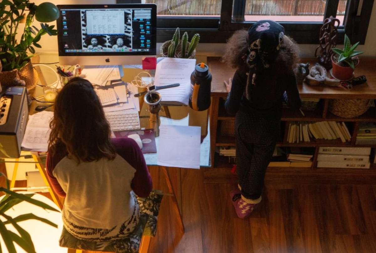 En la imagen de archivo, una mujer realiza teletrabajo en su casa mientras su hija juega a su lado.