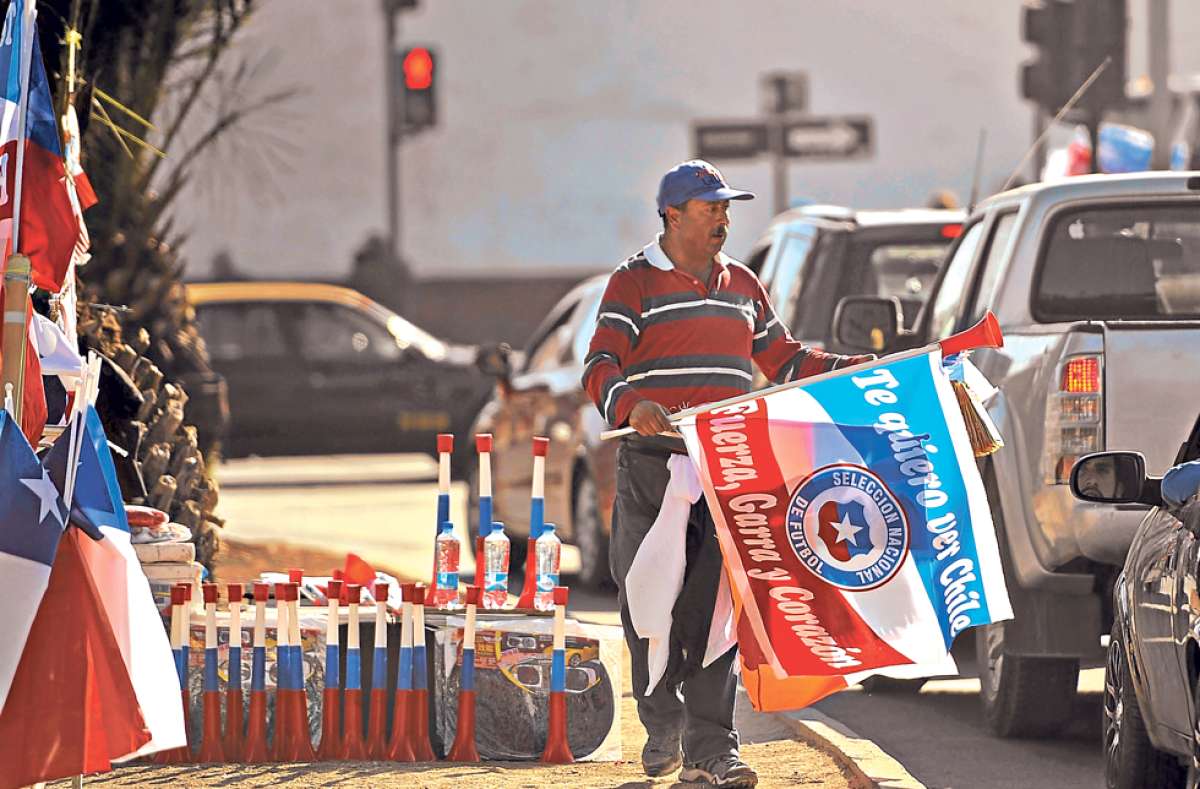 Un comerciante chileno vende banderas y vuvuzelas en una de las principales avenidas de Santiago. La capital chilena, sede principal del certamen continental, se futboliz&oacute; en las &uacute;ltimas semanas. Foto: AFP