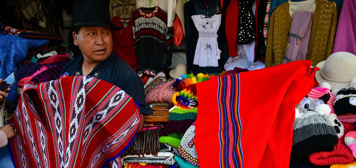 Luis Enrique Vinueza ense&ntilde;a una cacha de poncho (esta representa la unidad familiar) en su puesto de venta en el portal artesanal que a diario es visitado por turistas nacionales y extranjeros, as&iacute; como sus compradores de toda la vida.