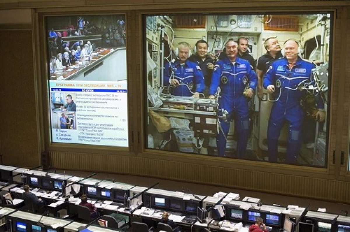 Imagen que muestra a la tripulaci&oacute;n de la nave Soyuz (en la pantalla gigante) durante una conexi&oacute;n en directo con el Centro de Control de Misiones ruso realizada tras alcanzar con &eacute;xito la Estaci&oacute;n Espacial Internacional (EEI). Foto: NASA cedida a EFE