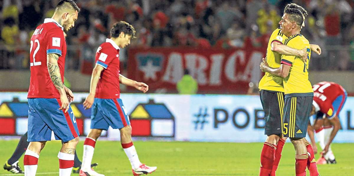 Los jugadores chilenos abandonan la cancha luego de ceder un empate ante los colombianos que festejan. AFP