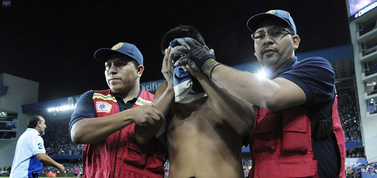  Dos param&eacute;dicos ayudan a un hincha de Emelec que result&oacute; afectado por el gas pimienta que lanzaron los polic&iacute;as en la general del estadio Capwell.