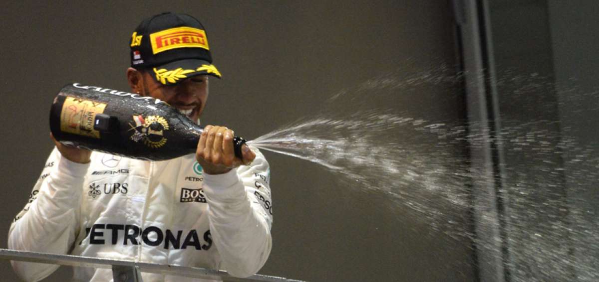 Lewis Hamilton festeja con champagne tras alcanzar el podio de la decimacuarta carrera de la temporada.