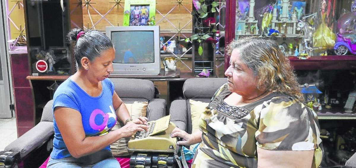 Margarita (der.) asienta sus dedos sobre el braille para descifrar las letras. La int&eacute;rprete Gina Soledispa escribe en la m&aacute;quina de teletacto.  