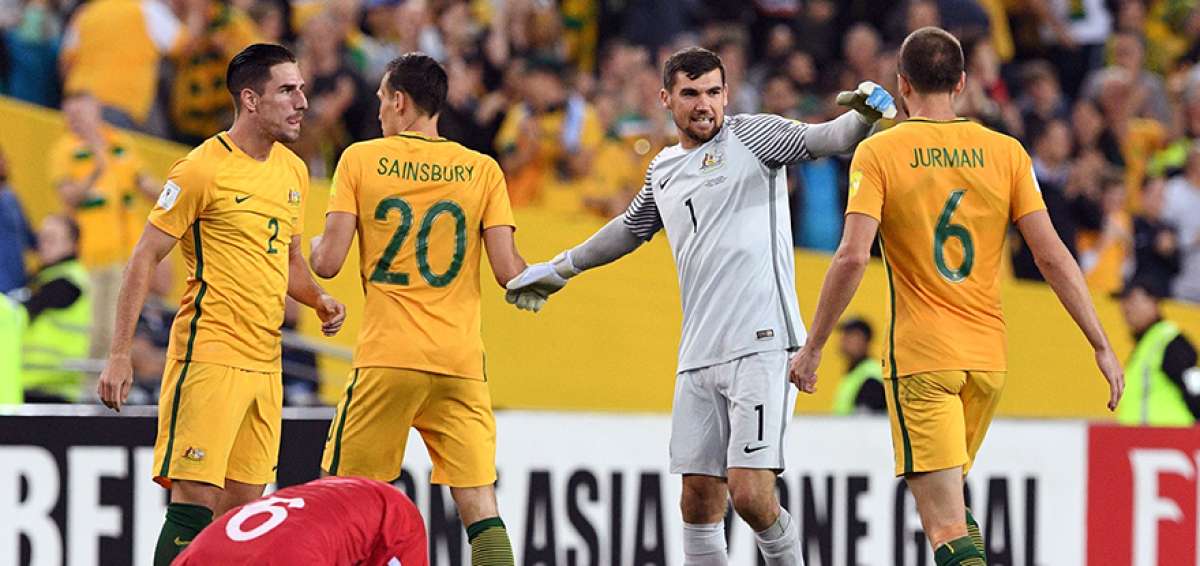 Los jugadores australianos festejan la clasificaci&oacute;n al repechaje mientras un seleccionado sirio se lamenta en el piso por la derrota.