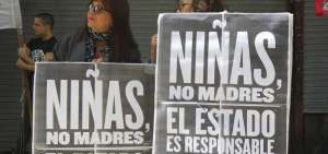 Dos mujeres sostienen carteles durante una protesta junto a decenas de personas en Buenos Aires (Argentina).
