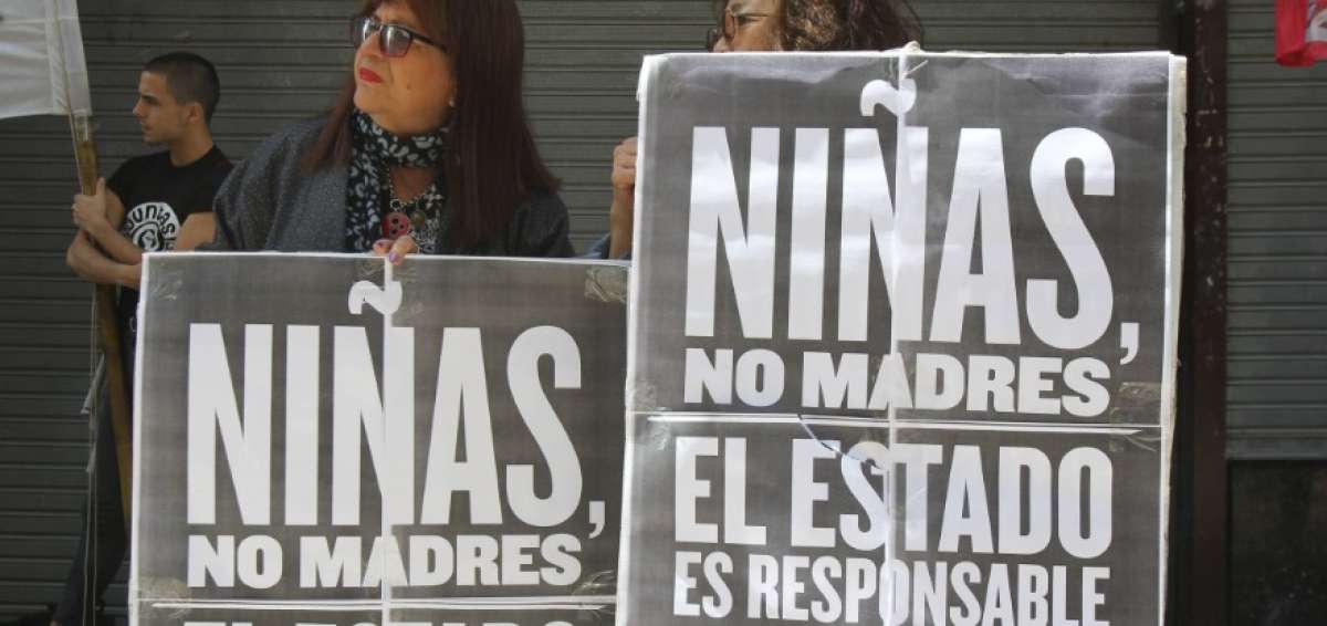 Dos mujeres sostienen carteles durante una protesta junto a decenas de personas en Buenos Aires (Argentina).