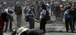 Un grupo de personas usa mascarillas sanitarias en las labores de limpieza de los escombros dejados por los disturbios durante las manifestaciones.