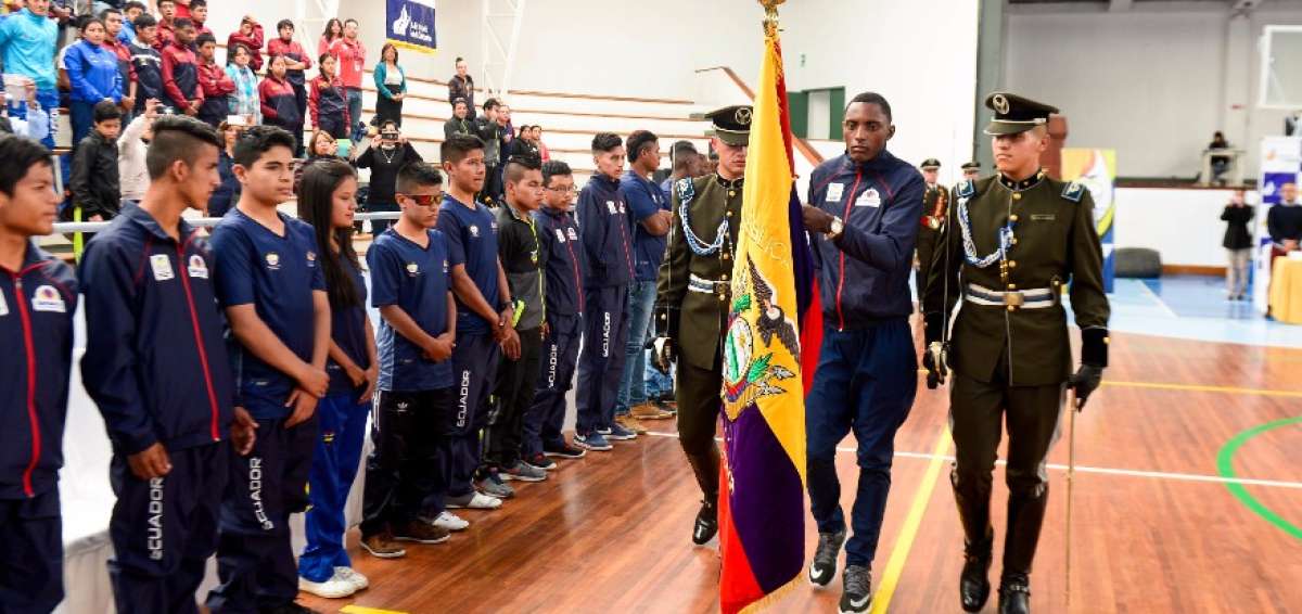 El atleta Dami&aacute;n Carcel&eacute;n lleva la bandera nacional, frente a sus compa&ntilde;eros deportistas.