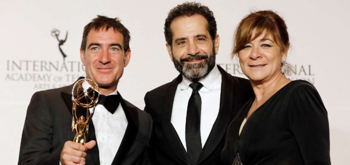 El actor estadounidense Tony Shalhoub (c) posa junto al guionista espa&ntilde;ol Alex Pina (i) y la productora ejecutiva Sonia Mart&iacute;nez (d) mientras sostienen su premio a Mejor Serie Dram&aacute;tica por "La casa de papel".