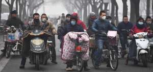  Envueltos por una nube t&oacute;xica, personas en bicicletas y motos cruzan una calle en la ciudad de Shijiazhuang, capital de la provincia de Hebei en el centro oriente de China.