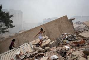 Personas caminan este jueves, entre los escombros de edificios afectados por los terremotos en La Guaira (Venezuela).