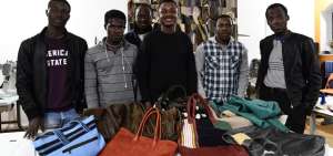 Bassirou (el tercero, de izq. a der.) muestra los bolsos que confecciona en Lai Momo, un programa que capacita a los migrantes que llegan a Italia.